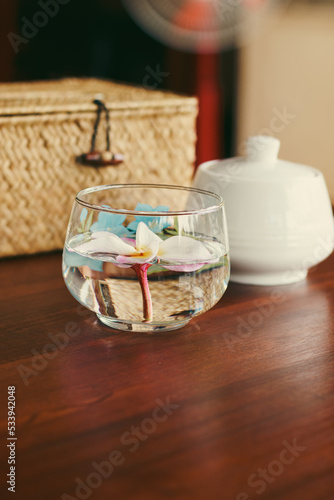 Vertical shot of a frangipani flower in a glass of water as a table centerpiece showing a relaxing living space, wellness and wellbeing