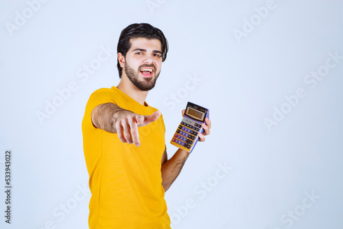 Man in yellow shirt working with calculator and looks happy because of results photo