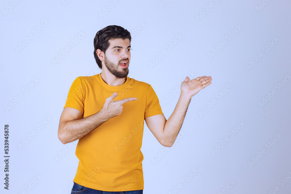 Man in yellow shirt showing something on the right Man in yellow shirt showing something on the right