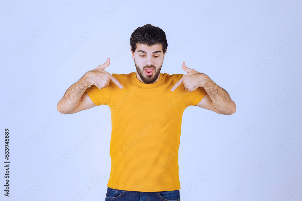 Man in yellow shirt pointing at himself Man in yellow shirt pointing at himself