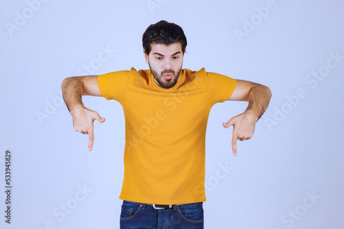 Man in yellow shirt pointing below © racool_studio
