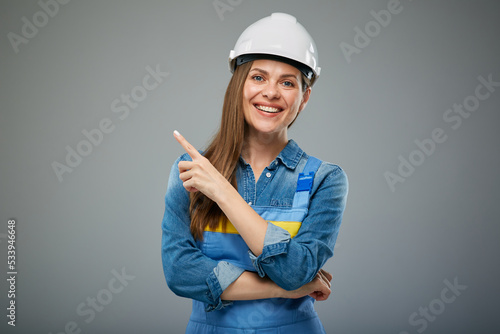 Woman architect or engineer wearing industrial helmet pointing with finger. Isolated female portrait.