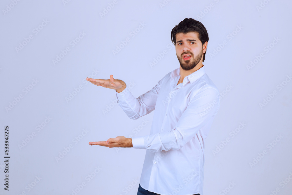 Man with beard in white shirt showing the dimensions of an estimated object Man with beard in white shirt showing the dimensions of an estimated object