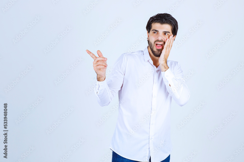 Man in white shirt pointing somewhere on the left with face emotions Man in white shirt pointing somewhere on the left with face emotions