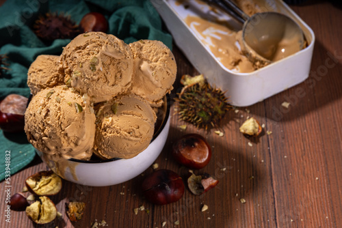 Autumn spicy ice cream with the roasted chestnut taste, with spices, on a wooden background with fresh and roasted chestnuts photo