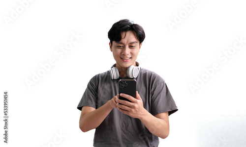 Asian man with headphones listening music using smartphone app while standing over isolated white background