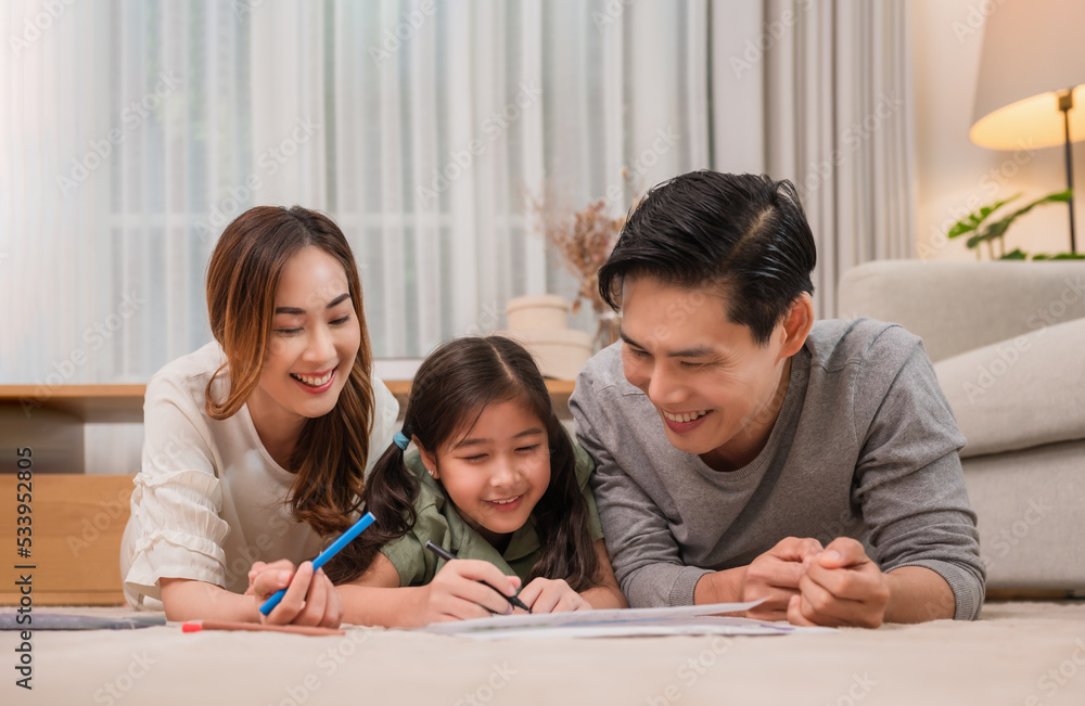 Happy Asian family father, mother, and daughter relaxing by playing and painting together on carpet in the living room at home. Happy Asian family father, mother, and daughter relaxing by playing and painting together on carpet in the living room at home.