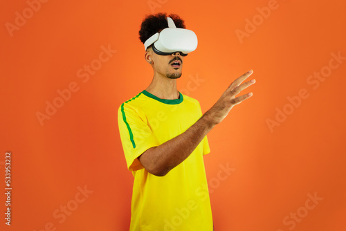 Brazilian Player - Black Man Celebrating With VR Virtual Glasses Isolated on Orange background