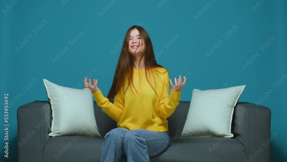 Overjoyed young girl student makes yes gesture, dances, feeling triumph, rejoicing goal achievement, sitting on sofa Overjoyed young girl student makes yes gesture, dances, feeling triumph, rejoicing goal achievement, sitting on sofa