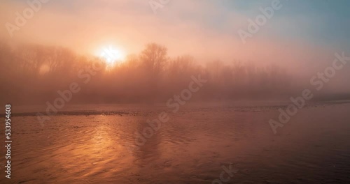 Mountain river time lapse at the summer or autumn sunrise. Wild nature, clear water and rural evergreen valley. Sun rays and heavy morning fog. Motorised dolly slider movement