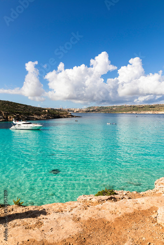 Playa del mediterraneo con aguas azules cristalinas con el cielo con nubes y un yate