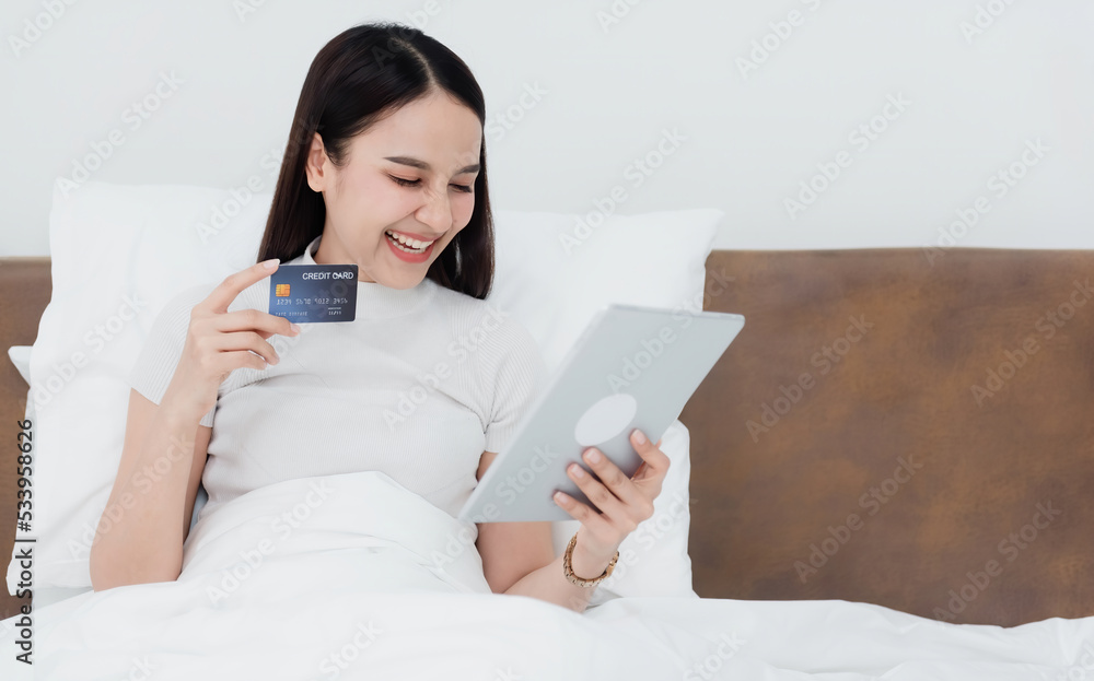 Asian beauty woman use a credit card to make purchases using a tablet through the internet With a happy smiling face, being a new normal online business In the shopping experience from home. Asian beauty woman use a credit card to make purchases using a tablet through the internet With a happy smiling face, being a new normal online business In the shopping experience from home.