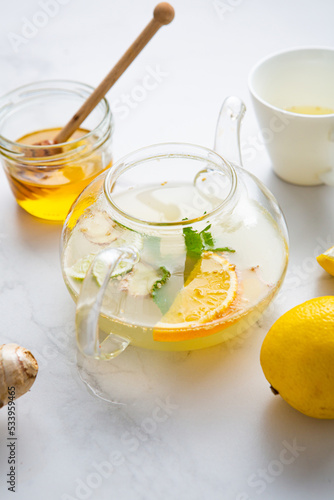 Close up of winter herbs spice and fruit lemon orange tea in glass teapot and honey