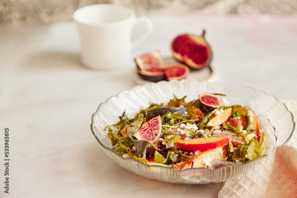 Mediterranean salad with fresh arugula, grain cheese, batata and figs, cup of tea. Healthy breakfast, fresh vegan salad Mediterranean salad with fresh arugula, grain cheese, batata and figs, cup of tea. Healthy breakfast, fresh vegan salad