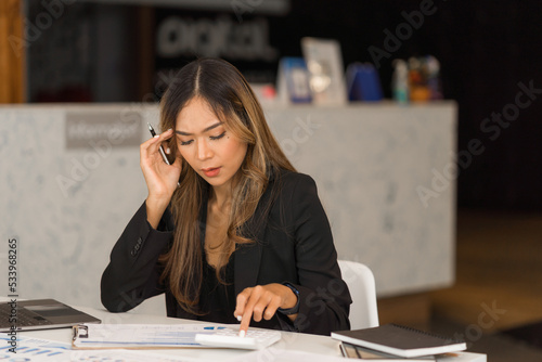 Tired asian businesswoman working at workstation.