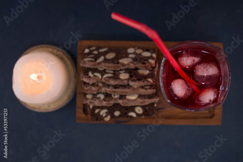 A glass of red juice with cake slices on a wooden platter, top view