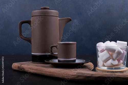 Coffee kettle with a cup and marshmallows on a wooden platter
