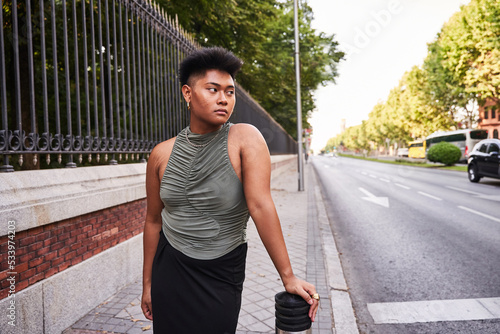 Non binary Filipino person standing near metal gate photo