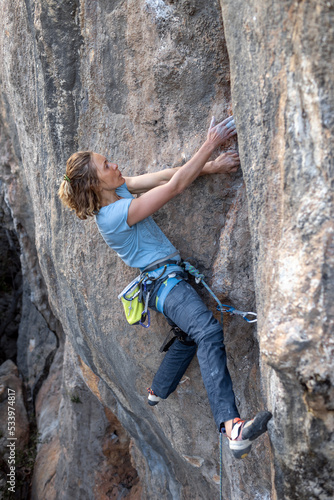 A woman climbs a rock