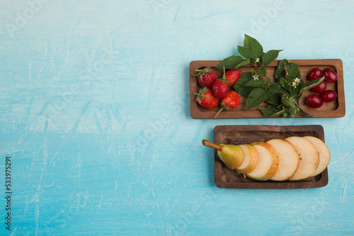 Sliced pears with strawberries and other berries in wooden platters
