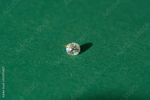 Antique white natural old style cut diamond loose gemstone setting with polished culet. Transparent precious natural cushion faceted European cut gem. Hardness 10. Green paper background. Daylight  © Sergejs
