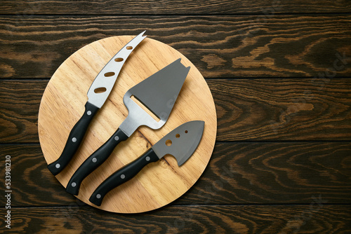 Cheese knife set on round cutting board, close-up, top view