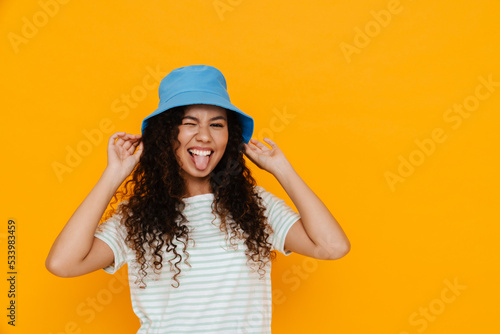 White curly woman wearing panama showing her tongue at camera © Drobot Dean