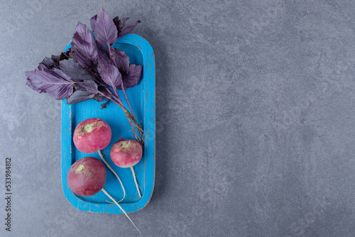 Purple basil with radishes on the board , on the marble background photo