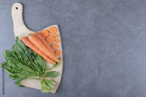 Watercress and carrots on the cutting board , on the marble background photo