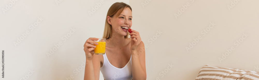 Young woman holding fresh cherry tomato and orange juice at home, banner. Young woman holding fresh cherry tomato and orange juice at home, banner.