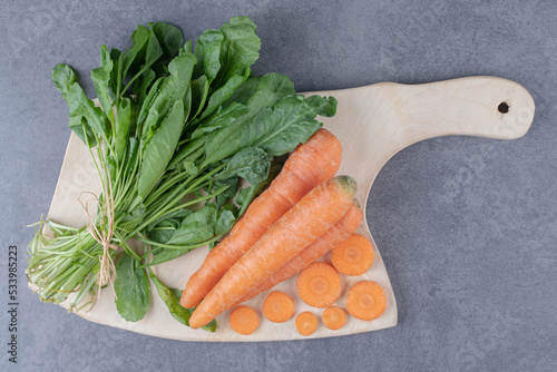 Watercress and carrots on the cutting board , on the marble background photo