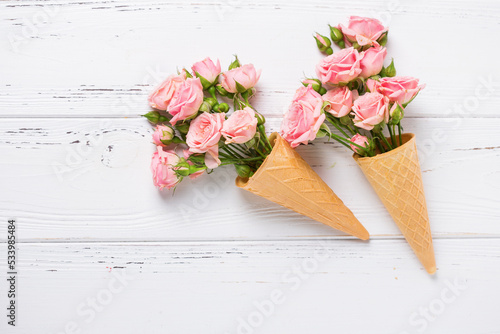 Floral still life flat lay. Pink summer roses on white textured wooden background. Place for text.