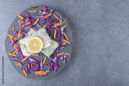 Sliced lemon, red cabbage and carrot with folded gutab , on the marble background photo