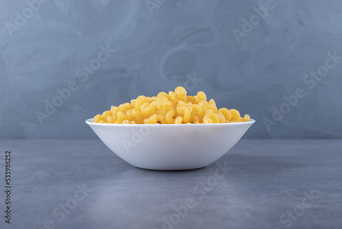 Raw elbow macaroni on white plate