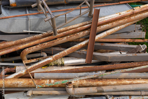 Old rusted metal pipes are lying around in a landfill. Environmental pollution by construction debris. Rusty water pipes.