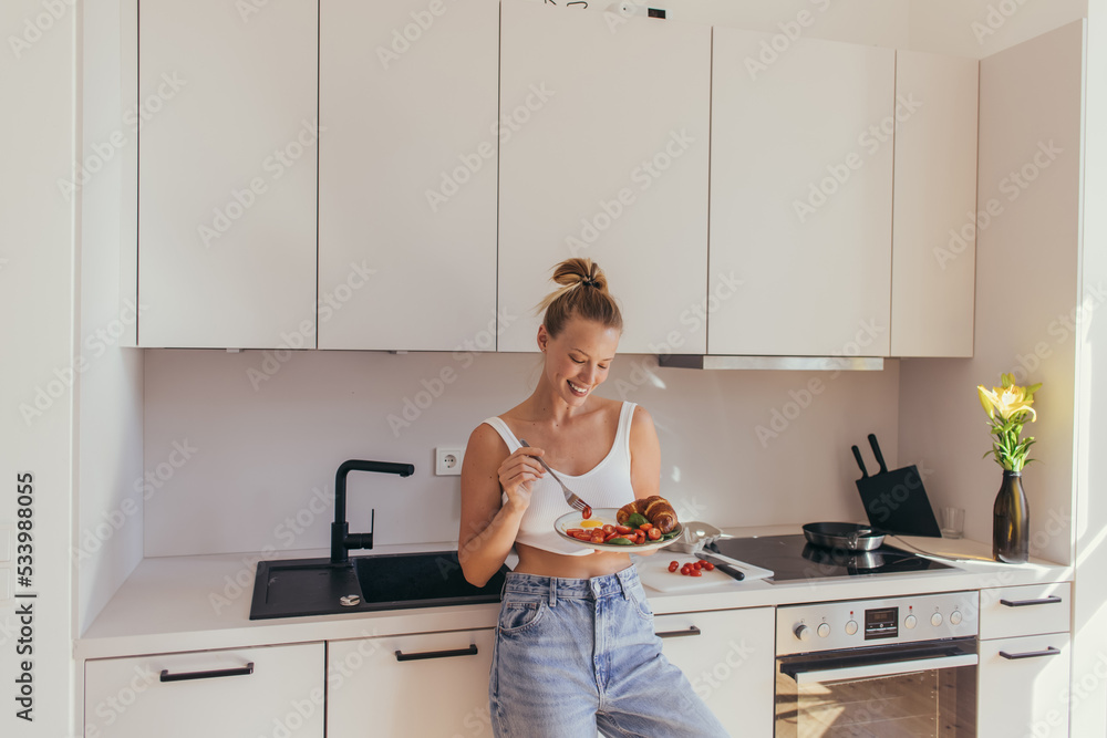 Smiling woman in top holding plate with breakfast in kitchen. Smiling woman in top holding plate with breakfast in kitchen.