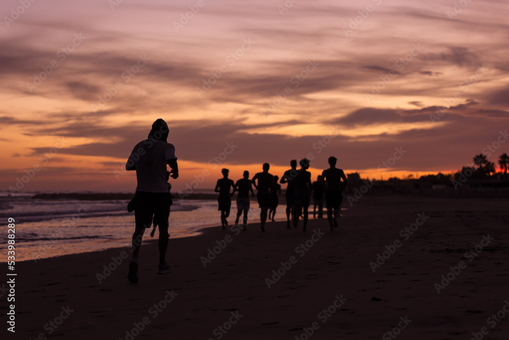 Silhouette of young fitness boys model of a soccer beach team jogging, running at sunrise sea in Rome Italy in a romantic sunset Silhouette of young fitness boys model of a soccer beach team jogging, running at sunrise sea in Rome Italy in a romantic sunset