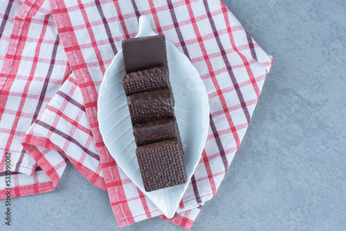 A bowl of chocolate coated on crispy wafer bar on the towel, on the marble background