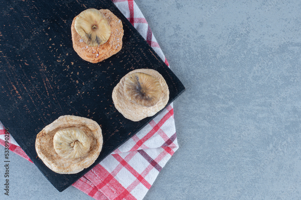 Dried figs on the cutting board, on the towel, on the tea towel, on the marble background