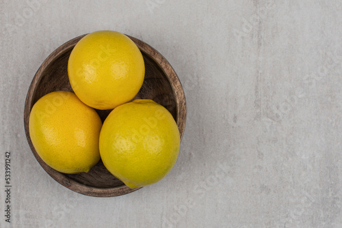Fresh sour lemons in wooden bowl