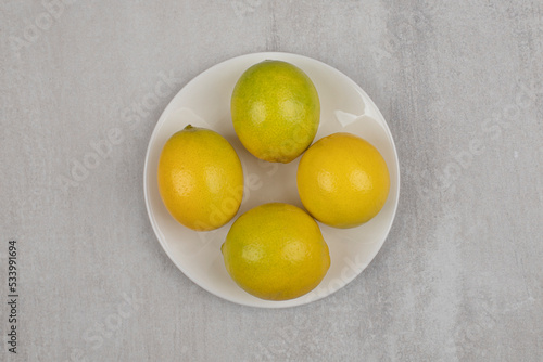 Fresh sour lemons on white plate
