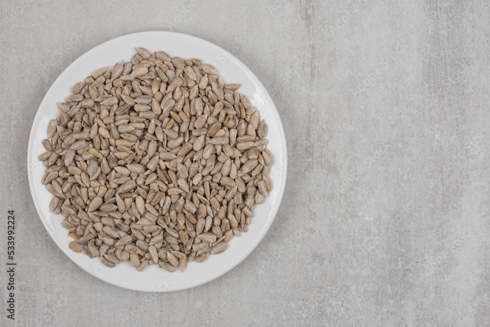 Pile of sunflower seeds on white plate Pile of sunflower seeds on white plate