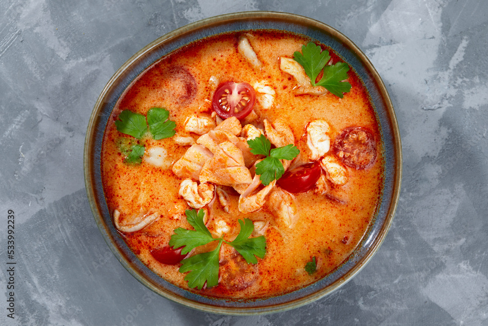 Traditional Thai food cuisine. Tom Yum spicy soup in black bowl on grey background. Thai food concept. Top view Traditional Thai food cuisine. Tom Yum spicy soup in black bowl on grey background. Thai food concept. Top view