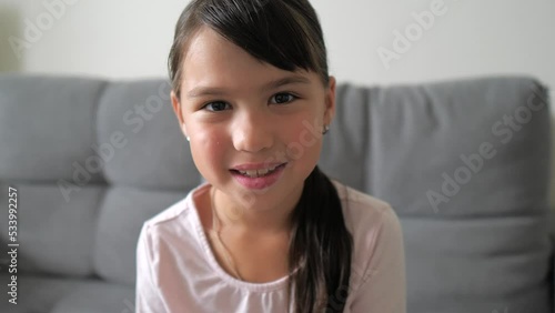 Close up portrait of caucasian little brunette girl in pink shirt smiling look at camera at home. Adorable kid smile with teeth. Happy childhood concept. 