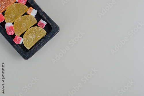 A dark wooden board full of colorful sugary marmalades photo