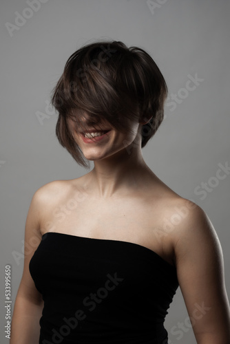 Beautiful girl upper body portrait. Smiling with wavy hair on face. .