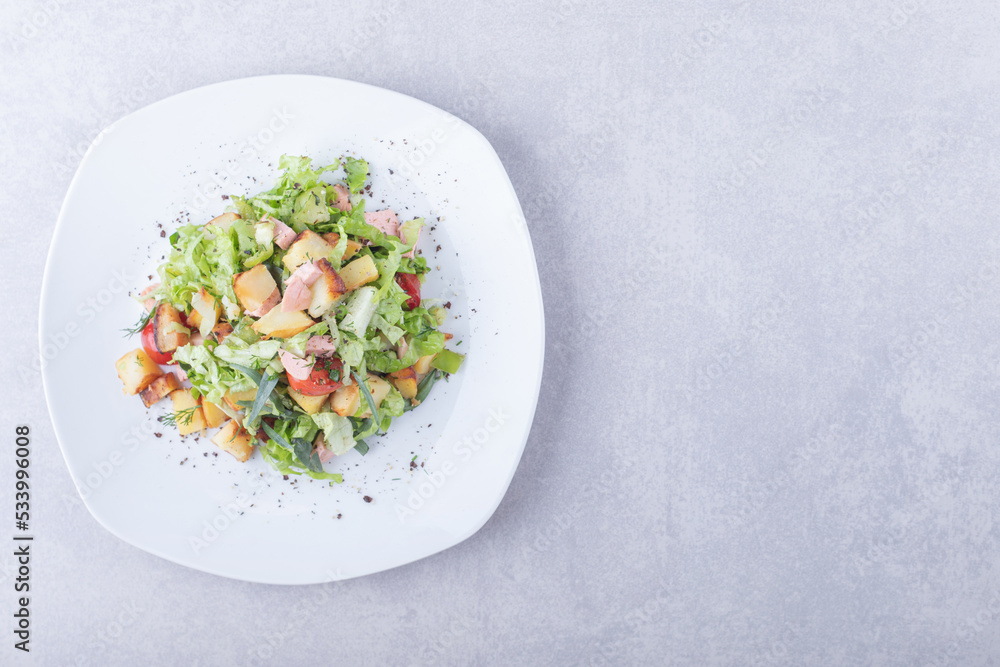 Plate of fresh salad with sausages on stone background Plate of fresh salad with sausages on stone background