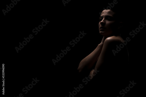 Portrait of a girl with short hair against dark background. Side lit contour slhouette...