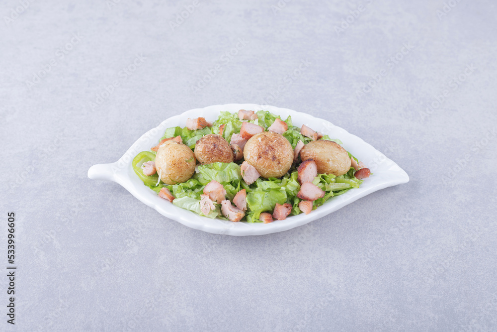 Sliced fried sausages and lettuce in white bowl Sliced fried sausages and lettuce in white bowl