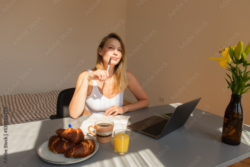 Pensive freelancer holding pen near breakfast and gadgets at home. Pensive freelancer holding pen near breakfast and gadgets at home.